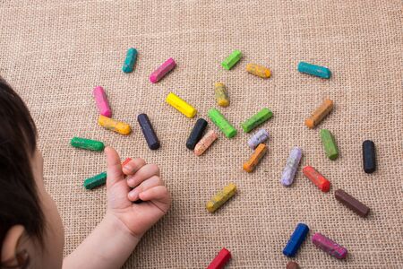 Used  color crayons and a toddlers hand on canvasの写真素材