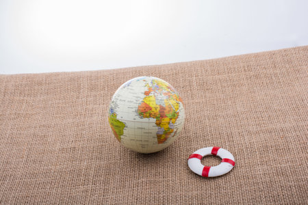 Life preserver beside a globe placed on canvas backgroundの写真素材