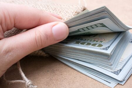 Hand holding banknote bundle of US dollar on a linen canvas backgroundの写真素材