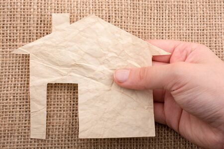 Hand holding a aper house on a canvas backgroundの写真素材