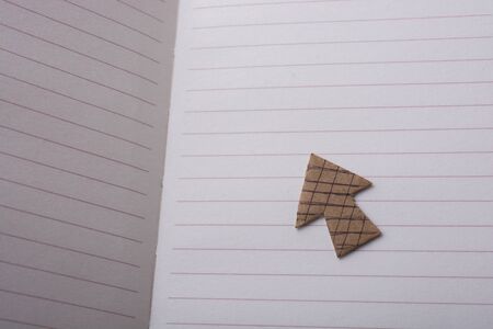 Arrow sign cut out of paper placed on paper on paperの写真素材