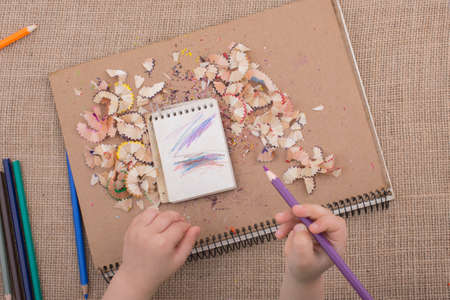 Hand holding a color pencil on spiral notebooks with pencil trashの写真素材