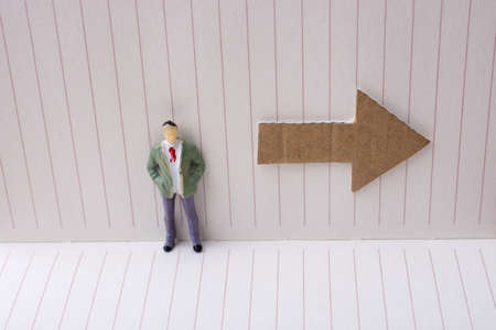 Figurine and an paper arrow in a notebook on canvasの写真素材