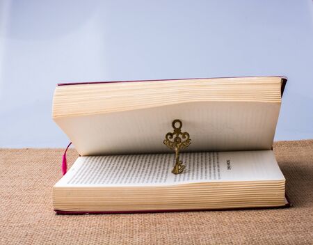 Retro style key placed in a book on a canvasbackgroundの写真素材