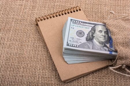 Banknote bundle of US dollar placed on a notebookの写真素材