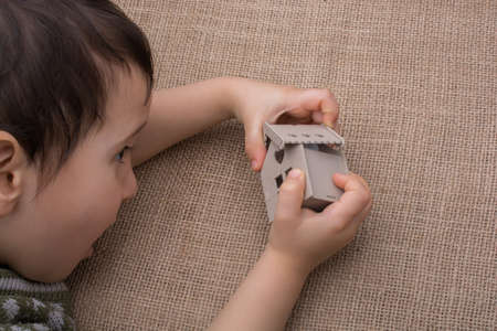 Child holding a model house on a linen canvasの写真素材