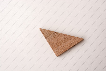 Piece of wood in the shpae of a triangle on paperの写真素材