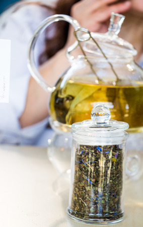 Herbal tea brewed in glass teapot and tea plant in a bottleの写真素材
