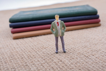 Man figurine standing beside little books on canvas