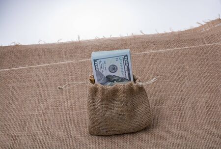 Banknote bundle of US dollarin a sack on a canvasの写真素材