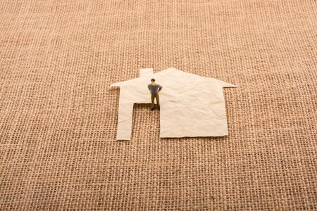 Man figurine and a house shape cut out of paperの写真素材