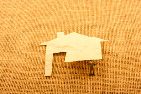 Man figurine and a house shape cut out of paperの写真素材