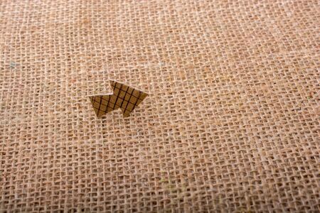 Arrow sign cut out of brown paper on canvasの写真素材