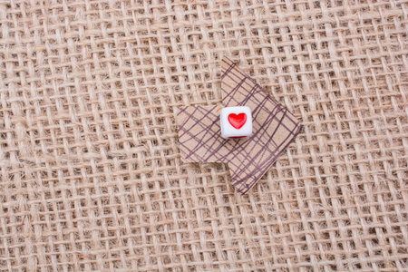 Love cubes on arrow cut out of brown paper on canvas