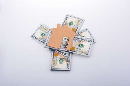 Paper house placed beside a bundle of US dollar banknoteの写真素材