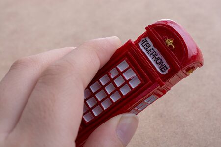 Hand holding a phone booth on a brown backgroundの写真素材