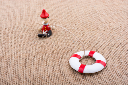 Pinocchio doll tied to a life preserver on canvasの写真素材