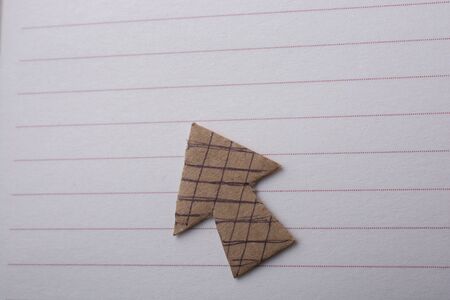 Arrow sign cut out of paper placed on paper on paperの写真素材