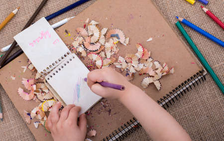 Hand holding a color pencil on spiral notebooks with pencil trashの写真素材