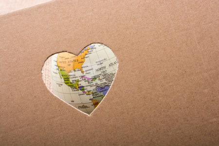 Globe seen through the heart shape hole on paper