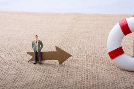Man figurine led by an arrow to Life preserver  on canvasの写真素材
