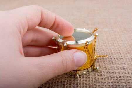 Hand holding a  toy drum on a canvas backgroundの写真素材