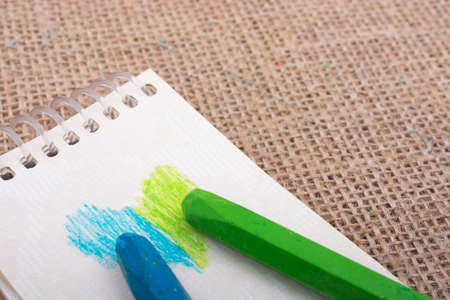 Notebook beside some colorful crayonsの写真素材