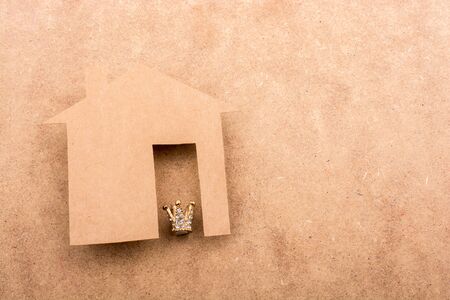 Litle model crown and paper house on a brown backgroundの写真素材