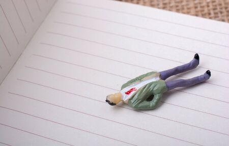 Man figurine relaxing on a lined white paperの写真素材