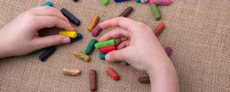Used  color crayons and a hand holding oneの写真素材