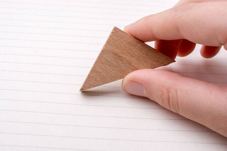 Piece of wood in the shpae of a triangle on paperの写真素材
