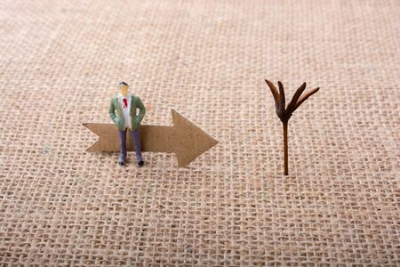 Figurine man led by an arrow on canvas backgroundの写真素材