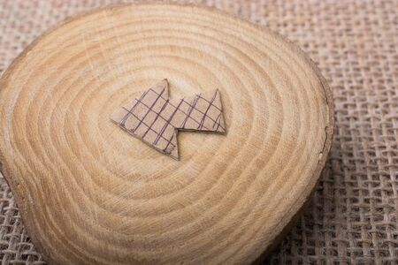 Arrow sign cut out of brown paper on piece of woodの写真素材