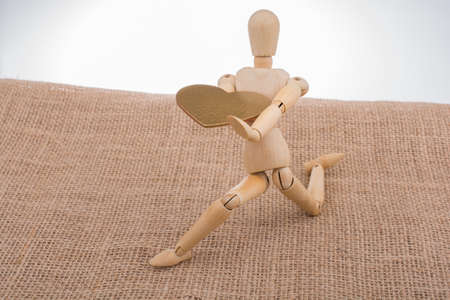 Heart shaped object  in the hand of a wooden man toyの写真素材