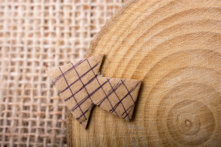 Arrow sign cut out of brown paper on piece of woodの写真素材