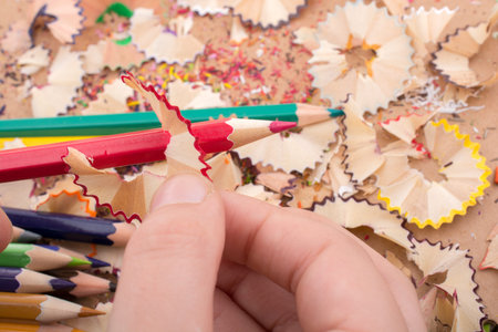 Colorful pencil shavings in hand on a notebook