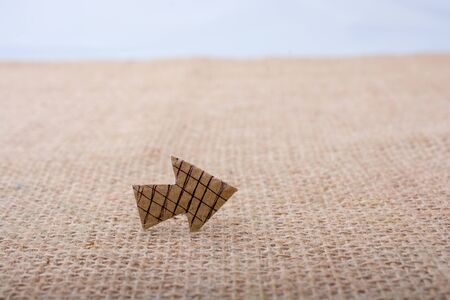 Arrow sign cut out of brown paper on canvasの写真素材