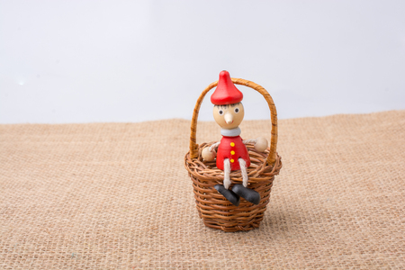 Pinocchio sitting on mini basket  on  canvasの写真素材