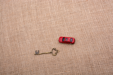 Key and a red toy car on a linen canvasの写真素材