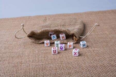 Colorful alphabet letter cubes out of sack on a canvasの写真素材
