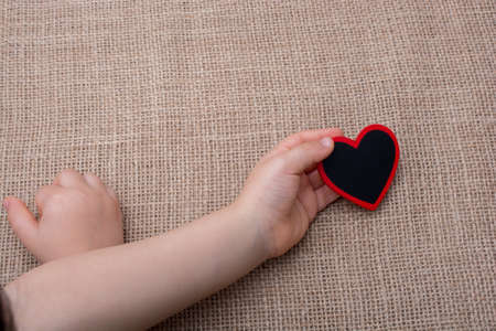 Heart shaped object in hand on canvasの写真素材