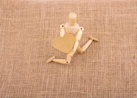 Heart shaped object  in the hand of a wooden man toyの写真素材
