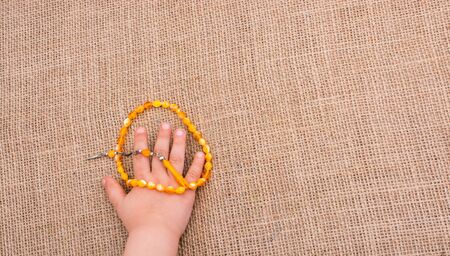 Set of praying beads of various colors in hand on canvasの写真素材