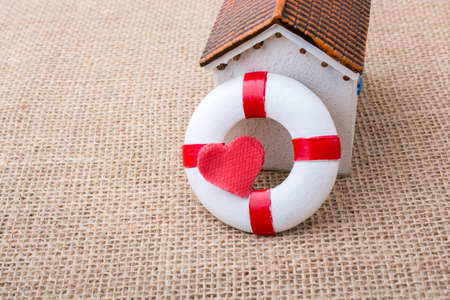 Model house and a life preserver with red heart shaped on itの写真素材