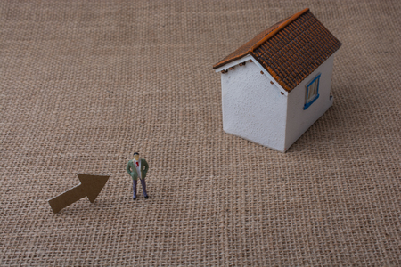 Model house and an arrow beside a man figure on a canvasの写真素材