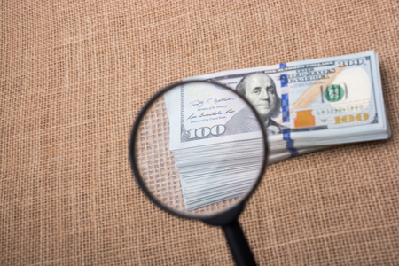 Magnifying glass  over the banknote bundle of US dollarの写真素材