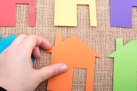 Little house shape cut out of colorful paper on a canvas background