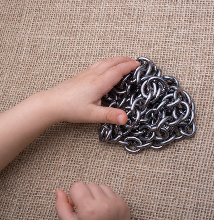 Chain made of metal in hand on canvas background