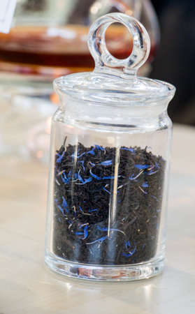 Herbal tea brewed in glass teapot and tea plant in a bottleの写真素材