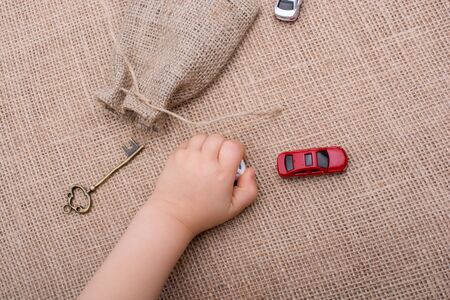Key, toy cars, human figures and a sack on a canvasの写真素材